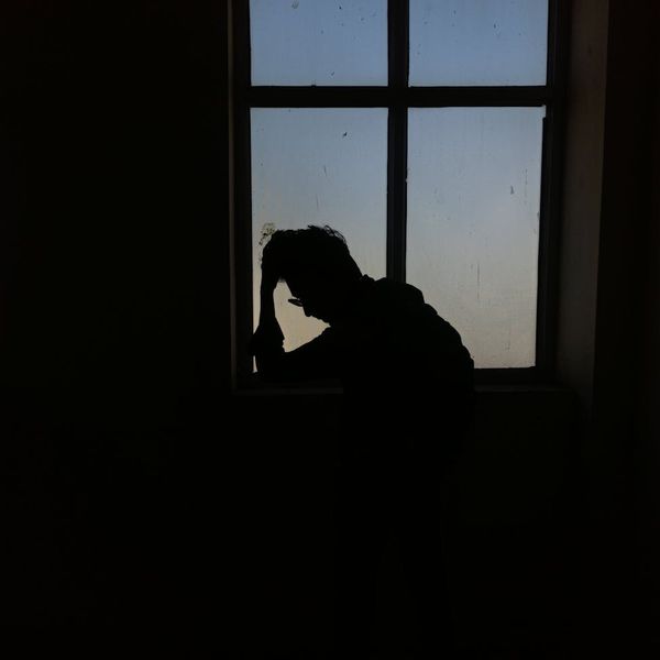 Person meditating peacefully near a window with soft light.
